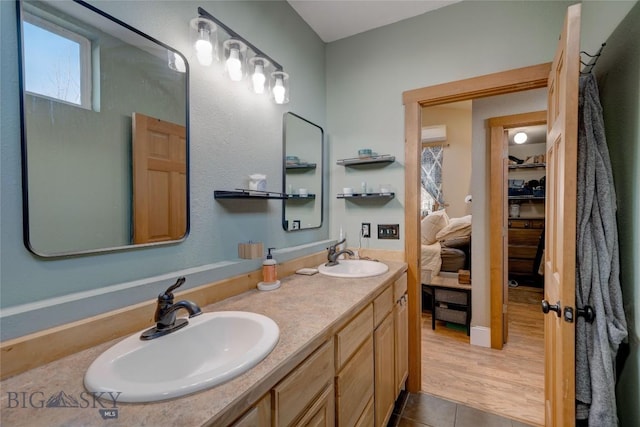 bathroom featuring double vanity, tile patterned flooring, a walk in closet, and a sink