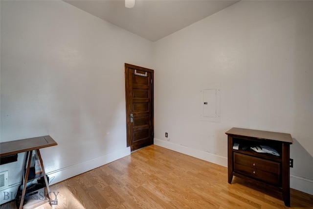 interior space featuring electric panel, baseboards, and light wood-style floors