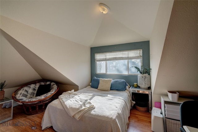 bedroom with vaulted ceiling and wood finished floors