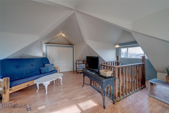 interior space with an upstairs landing, wood finished floors, and vaulted ceiling