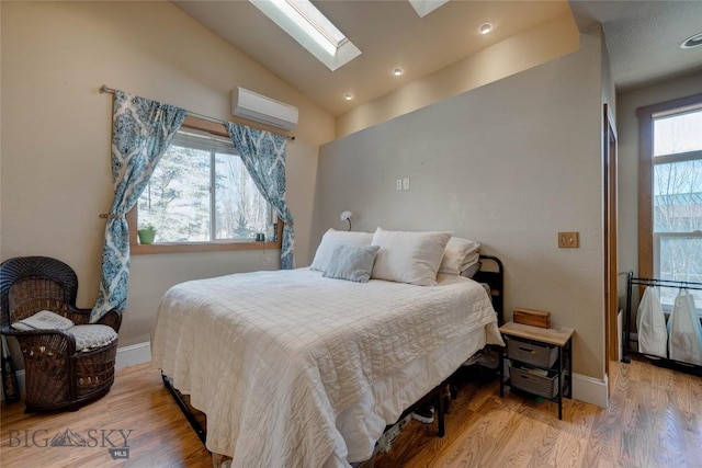 bedroom with an AC wall unit, wood finished floors, recessed lighting, vaulted ceiling with skylight, and baseboards