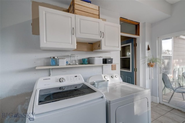 laundry room featuring washer and dryer, cabinet space, and light tile patterned flooring