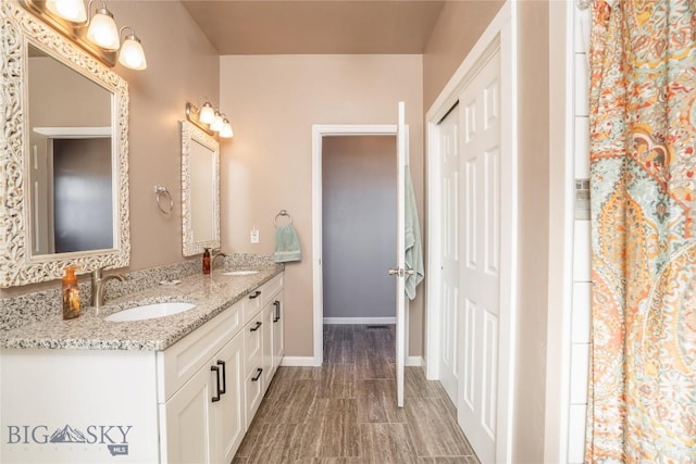 bathroom featuring double vanity, baseboards, and a sink