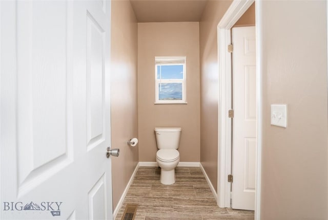 bathroom with visible vents, toilet, baseboards, and wood finished floors