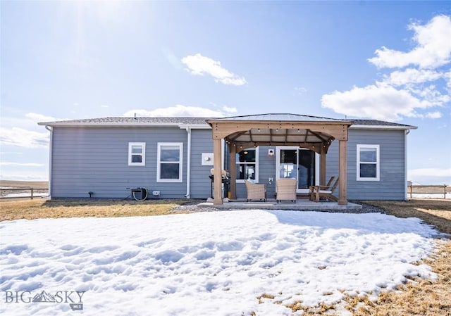 snow covered rear of property featuring a gazebo and fence