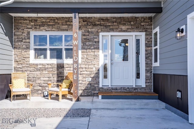 view of exterior entry featuring stone siding and a porch