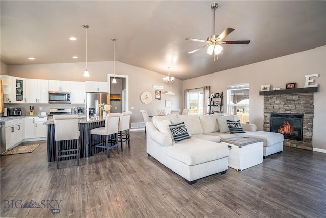 living room with high vaulted ceiling, dark wood-type flooring, ceiling fan with notable chandelier, a fireplace, and baseboards