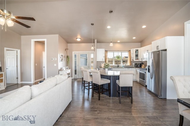 kitchen with a kitchen bar, open floor plan, dark wood-style floors, appliances with stainless steel finishes, and glass insert cabinets