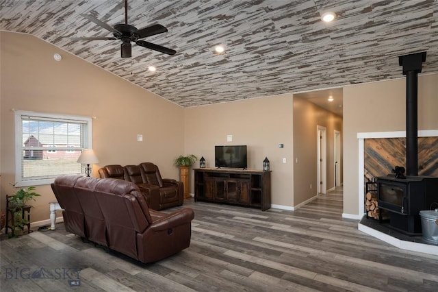 living area with high vaulted ceiling, a ceiling fan, wood finished floors, baseboards, and a wood stove