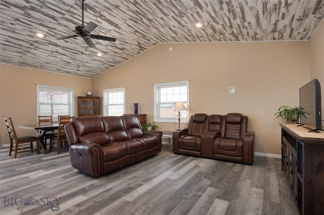 living area with a wealth of natural light, lofted ceiling, baseboards, and wood finished floors