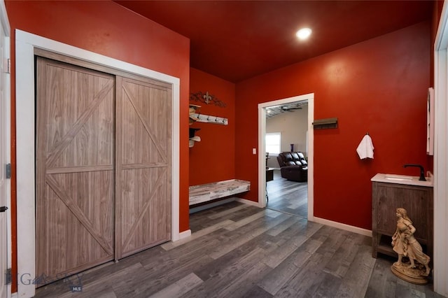 hallway featuring a sink, baseboards, and wood finished floors