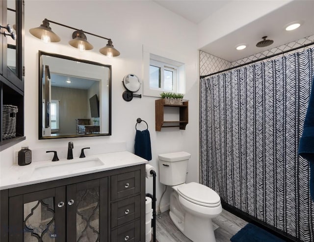 full bath with a shower with curtain, toilet, wood finished floors, and vanity