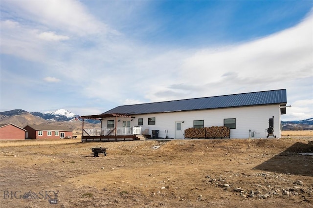 rear view of property with a deck with mountain view and metal roof