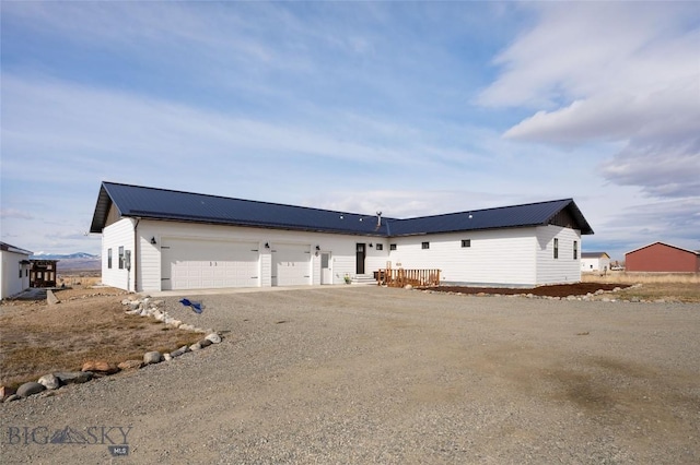 exterior space featuring driveway, metal roof, and an attached garage