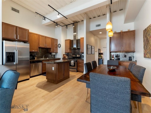 kitchen with visible vents, stainless steel appliances, a high ceiling, and wall chimney range hood