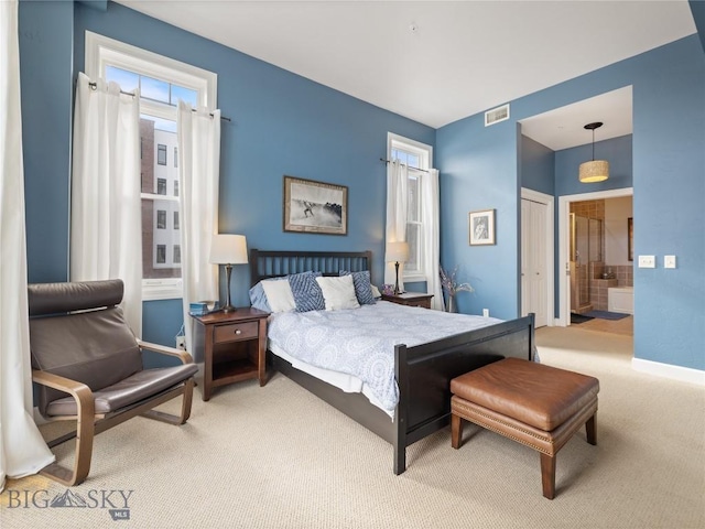 carpeted bedroom featuring ensuite bath, baseboards, and visible vents