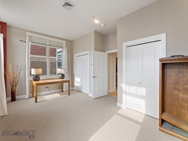 office area with baseboards, visible vents, and light carpet