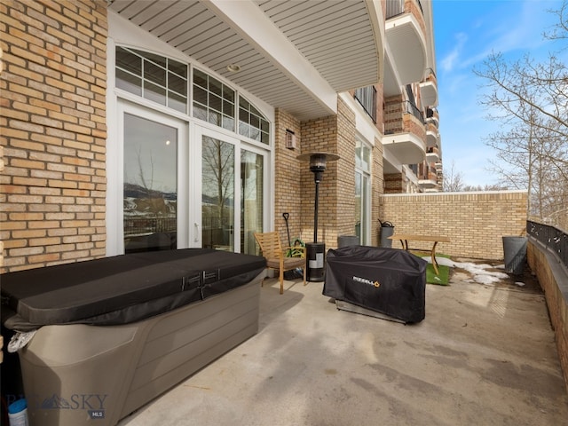 view of patio / terrace featuring grilling area, fence, and a hot tub