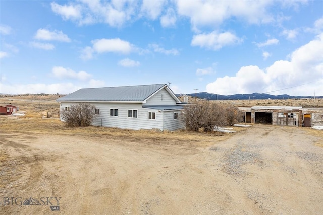 view of side of home featuring a mountain view, metal roof, and dirt driveway