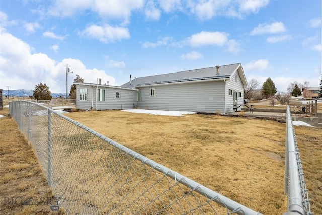 back of property with metal roof, a lawn, a fenced backyard, and a patio area