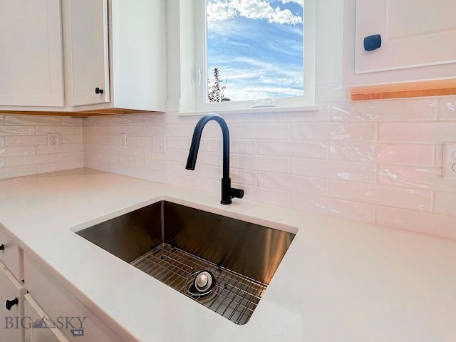 details with a sink, backsplash, white cabinets, and light countertops