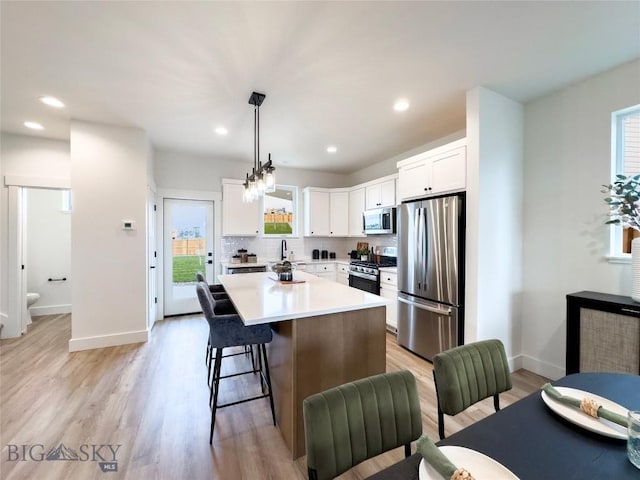 kitchen featuring plenty of natural light, white cabinets, stainless steel appliances, and light wood-style flooring