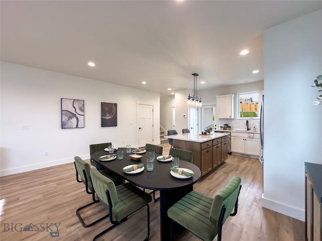 dining room featuring stairway, light wood-style flooring, and baseboards