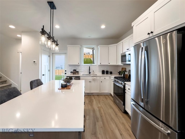 kitchen featuring decorative backsplash, light countertops, appliances with stainless steel finishes, and a sink