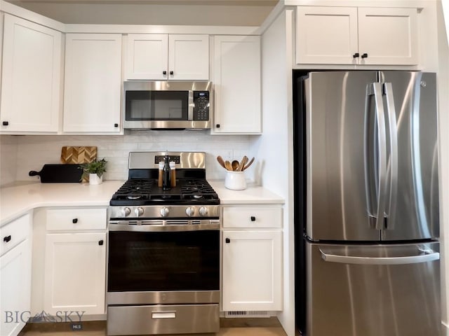 kitchen with stainless steel appliances, backsplash, and white cabinets