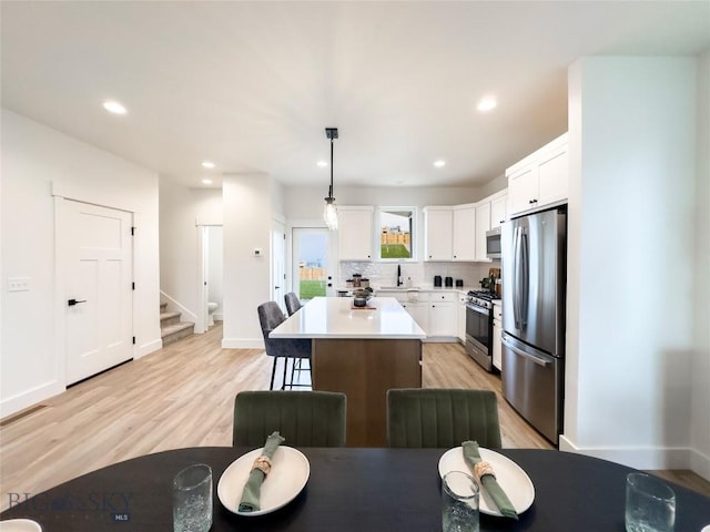 kitchen featuring stainless steel appliances, a kitchen island, light countertops, and white cabinetry