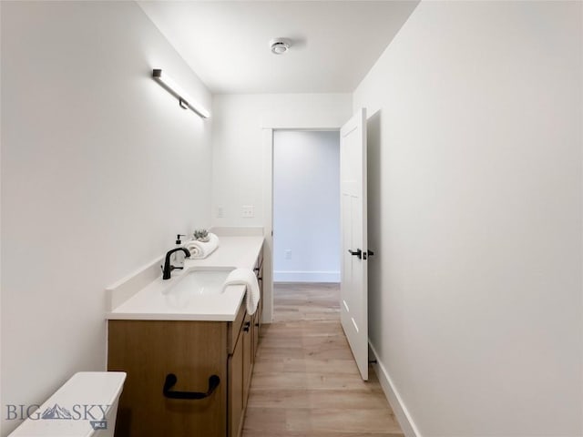 bathroom featuring vanity, wood finished floors, and baseboards