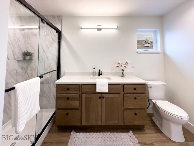 full bathroom featuring vanity, toilet, wood finished floors, and a marble finish shower