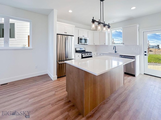 kitchen with visible vents, light wood-type flooring, decorative backsplash, appliances with stainless steel finishes, and a sink