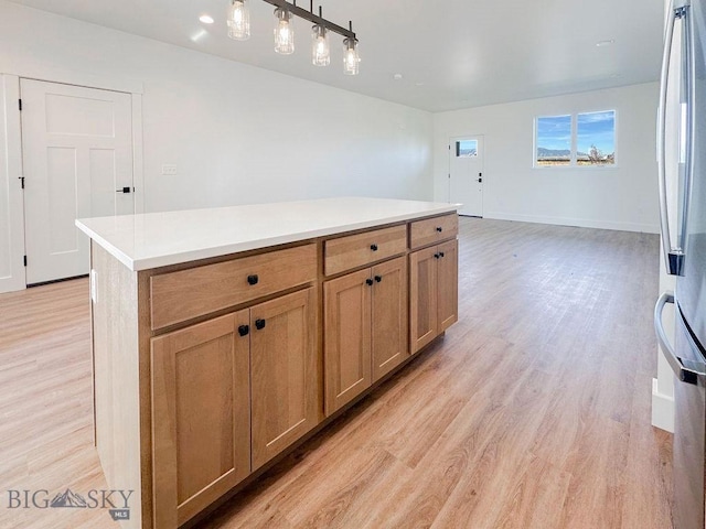 kitchen with light countertops, light wood-style floors, freestanding refrigerator, and a center island