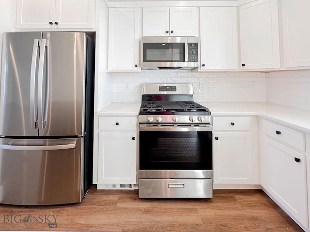 kitchen with white cabinets, stainless steel appliances, light countertops, and light wood-style floors