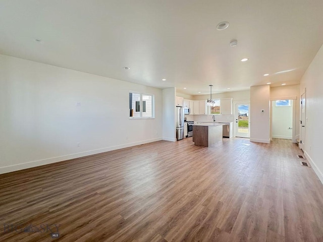 unfurnished living room featuring recessed lighting, baseboards, and wood finished floors