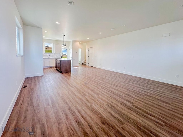 unfurnished living room featuring visible vents, baseboards, recessed lighting, stairs, and light wood-style floors