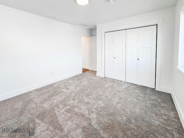 unfurnished bedroom with baseboards, carpet floors, and a closet