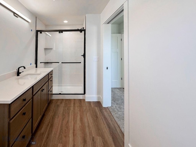 full bath featuring a stall shower, vanity, and wood finished floors