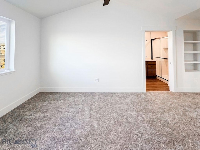 unfurnished bedroom with vaulted ceiling, ensuite bath, baseboards, and carpet floors