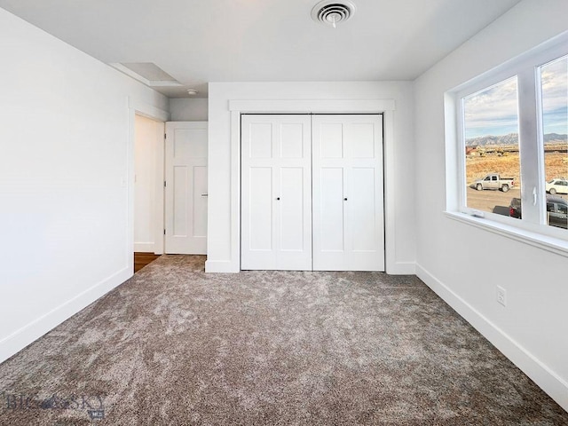 unfurnished bedroom featuring visible vents, baseboards, carpet, and a closet