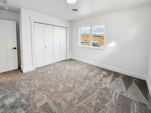 unfurnished bedroom featuring carpet, visible vents, a closet, and baseboards