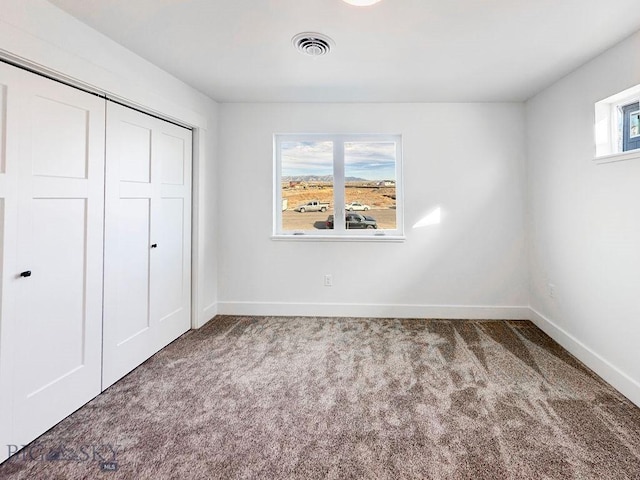 unfurnished bedroom with a closet, visible vents, carpet flooring, and baseboards