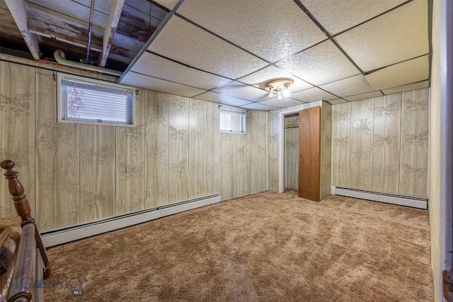 below grade area featuring a baseboard heating unit, carpet, and wood walls