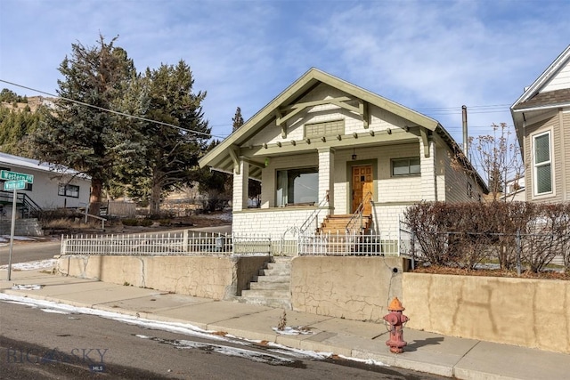 bungalow-style home with covered porch and a fenced front yard