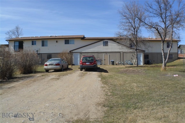 view of front of house with an outdoor structure, a front yard, and dirt driveway