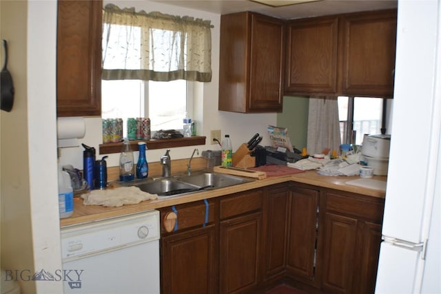 kitchen with brown cabinets, dishwasher, light countertops, and a sink