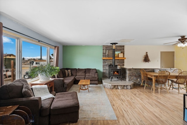 living room featuring a wood stove, wood finished floors, and ceiling fan