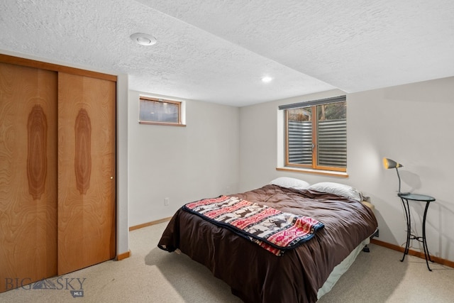 carpeted bedroom with a closet, baseboards, and a textured ceiling