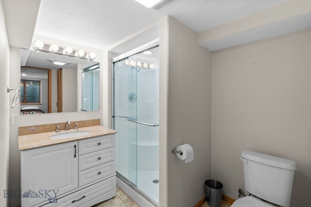 bathroom with tile patterned floors, toilet, a textured ceiling, a shower stall, and vanity